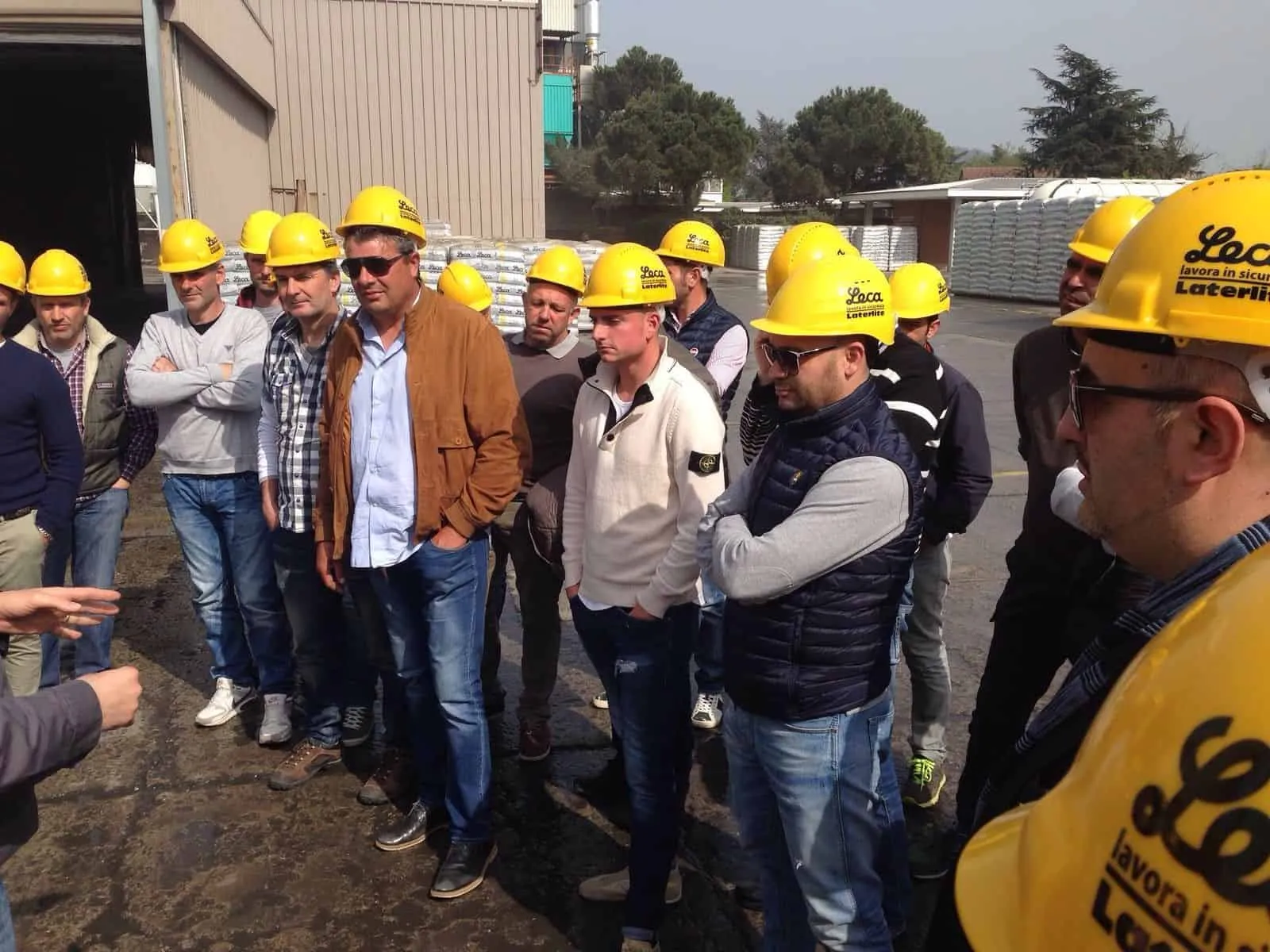 Gruppo di professionisti clienti Pieroni con elmetti di sicurezza gialli ascoltano attentamente