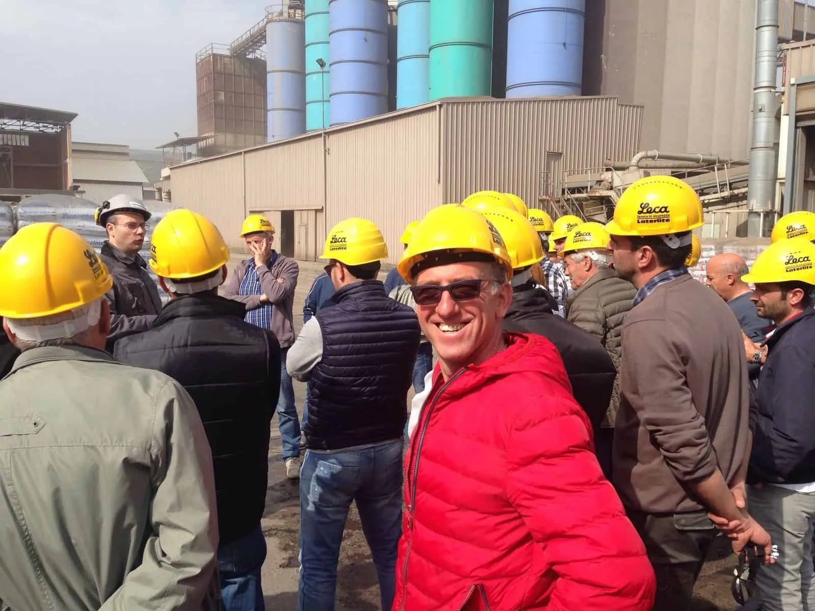 Gruppo di professionisti clienti Pieroni con elmetti di sicurezza gialli e uno dei nostri clienti che sorride